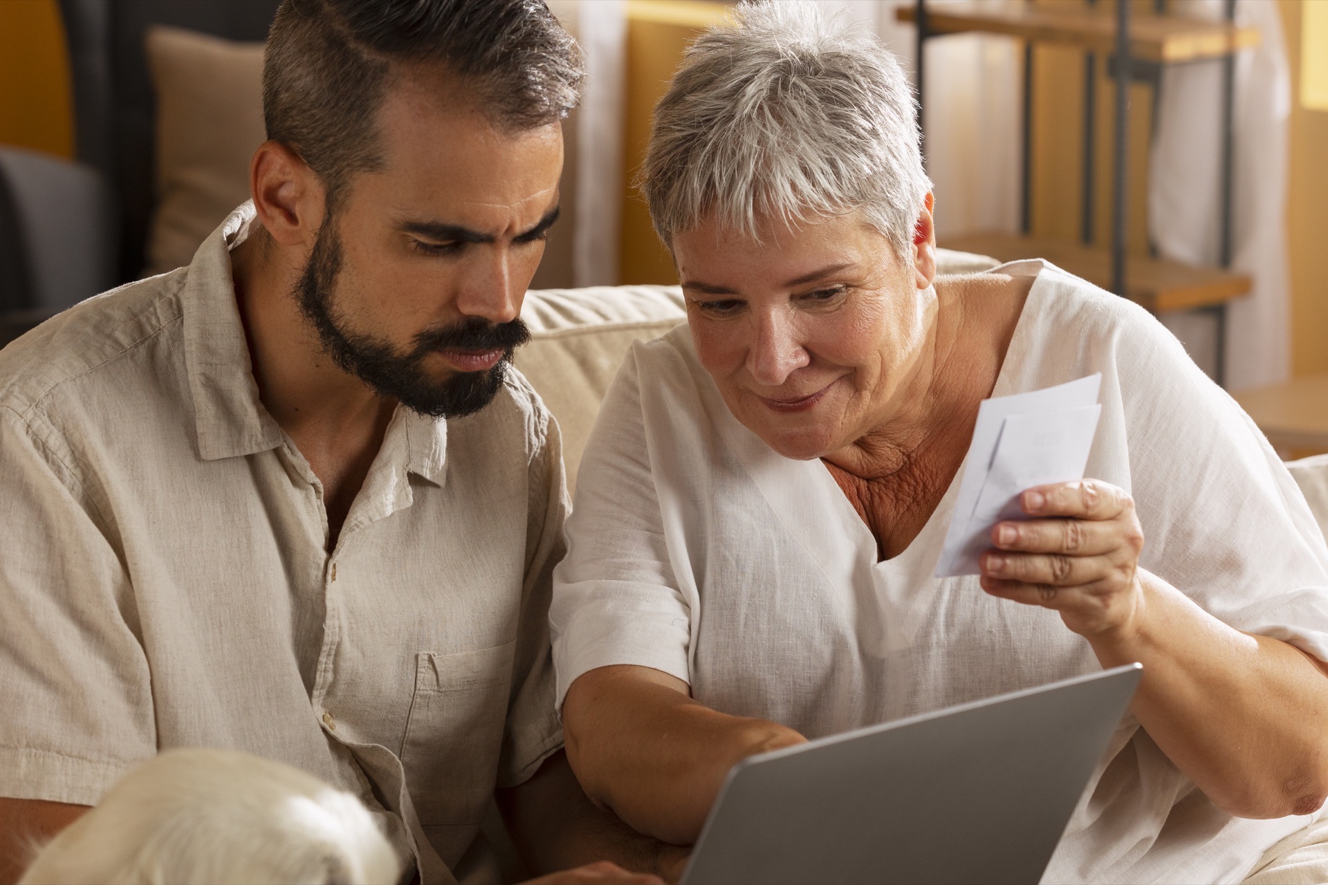 A man and an older woman reviewing healthcare options together on a laptop at home